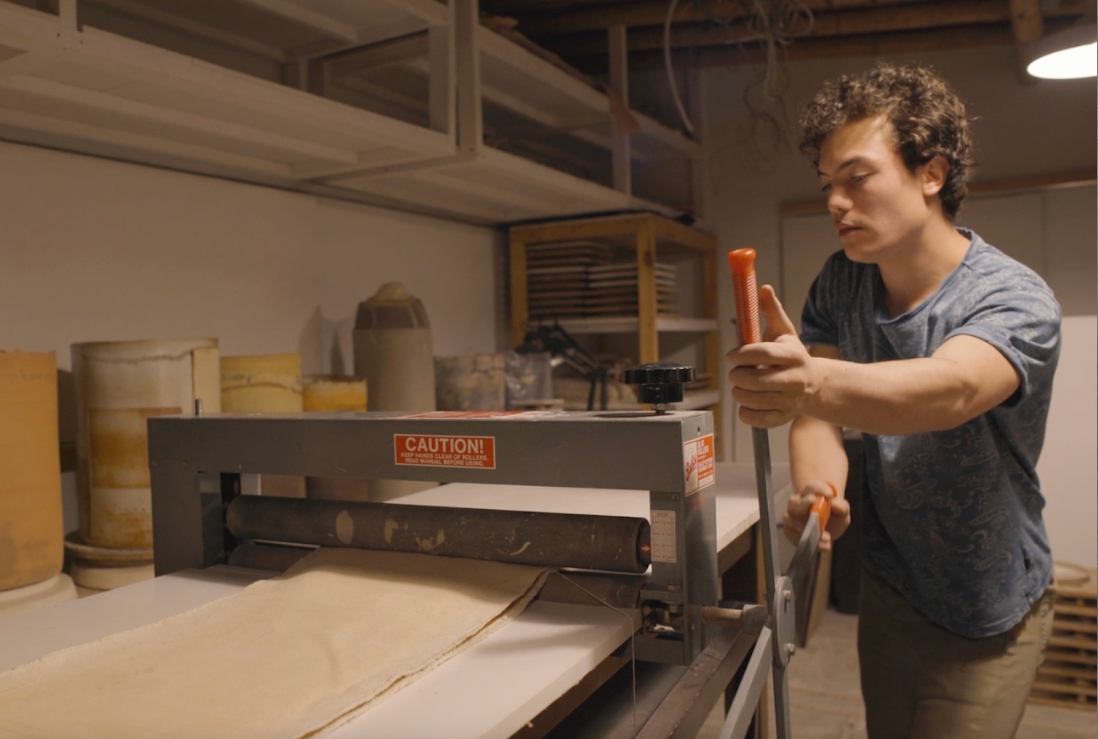 Artist operating a printing press in the studio.