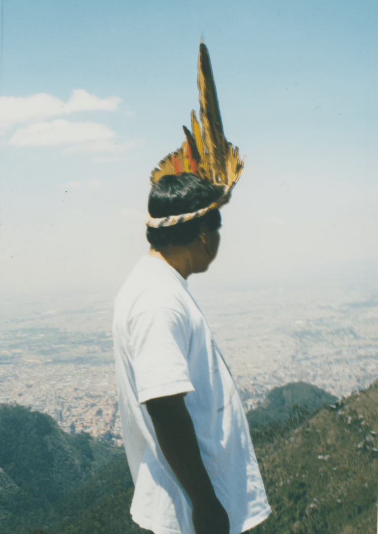Person wearing a feathered headdress overlooking Bogotá from the Eastern Andes.