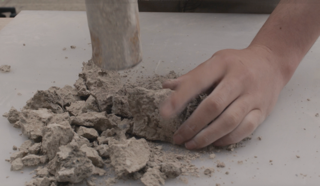 Hand crumbling earth material during the studio process.