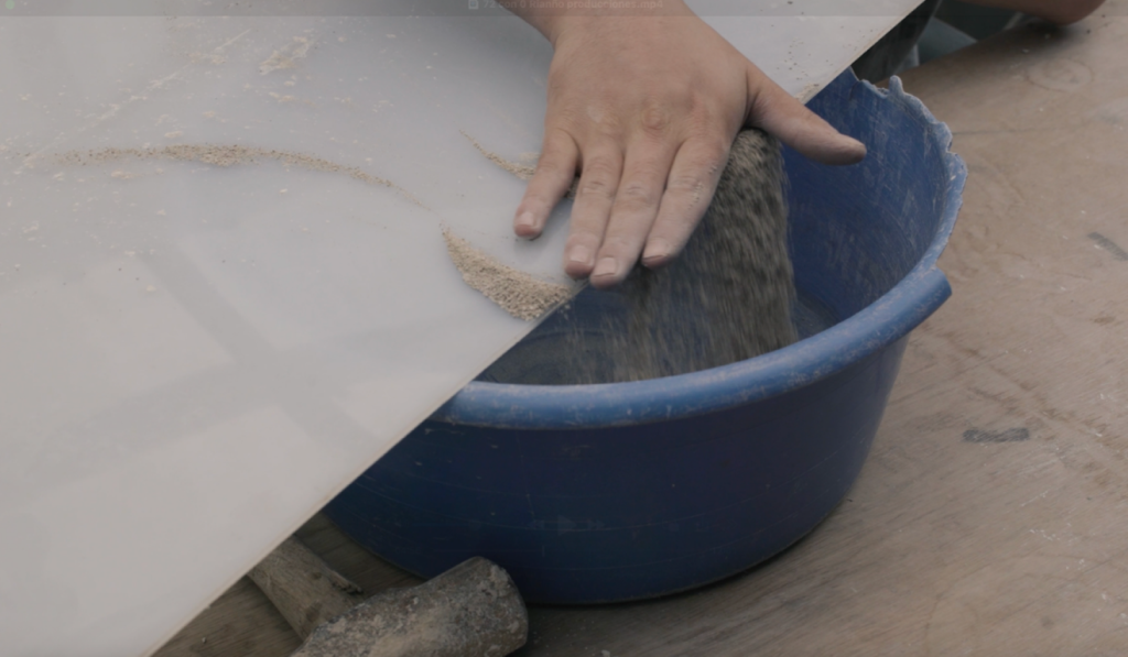 Hand washing fiber material in a blue basin.